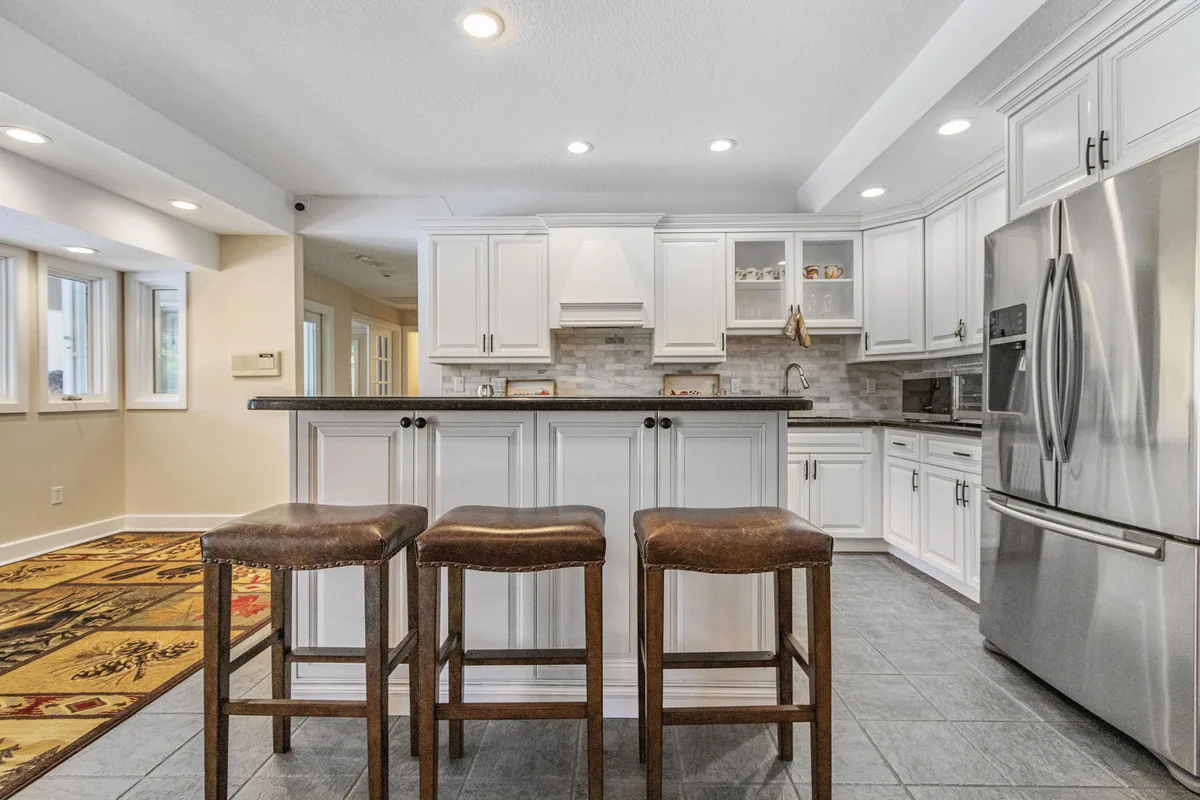 White kitchen with a breakfast bar and three leather stools