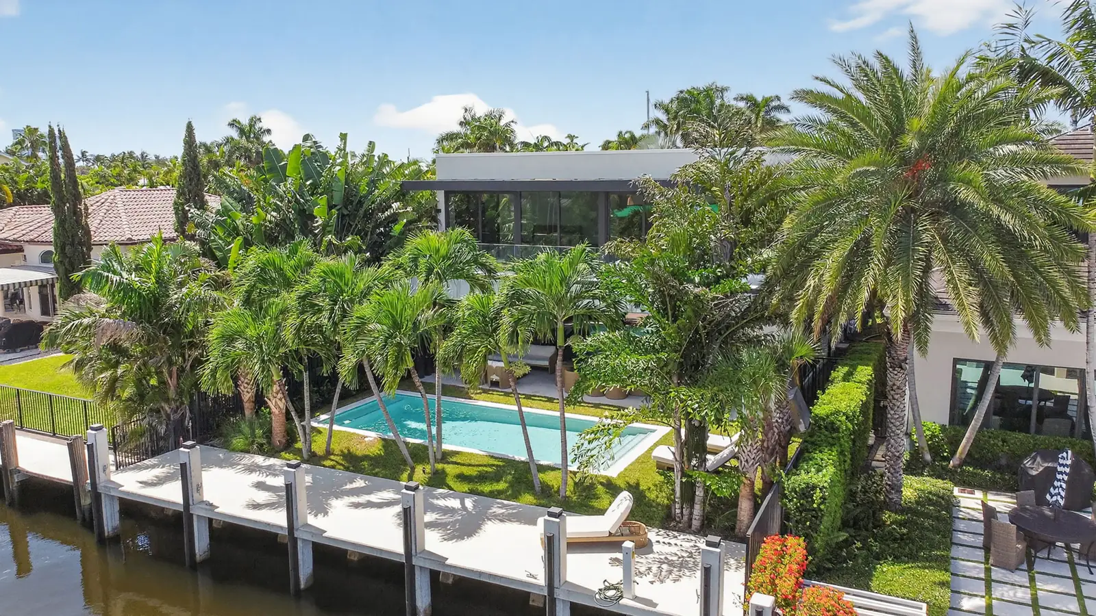 Aerial of the rear yard, pool and dock along a canal lined with homes