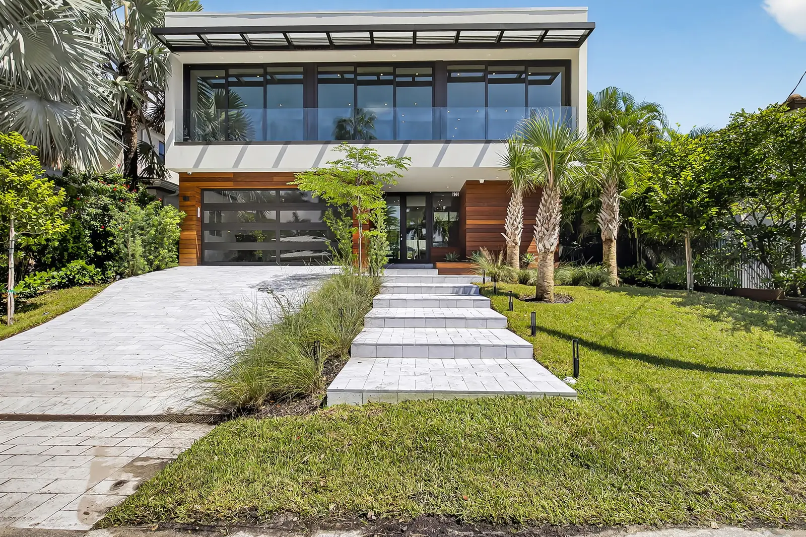 Front approach of a modern two-story home with a stepped walkway and palms