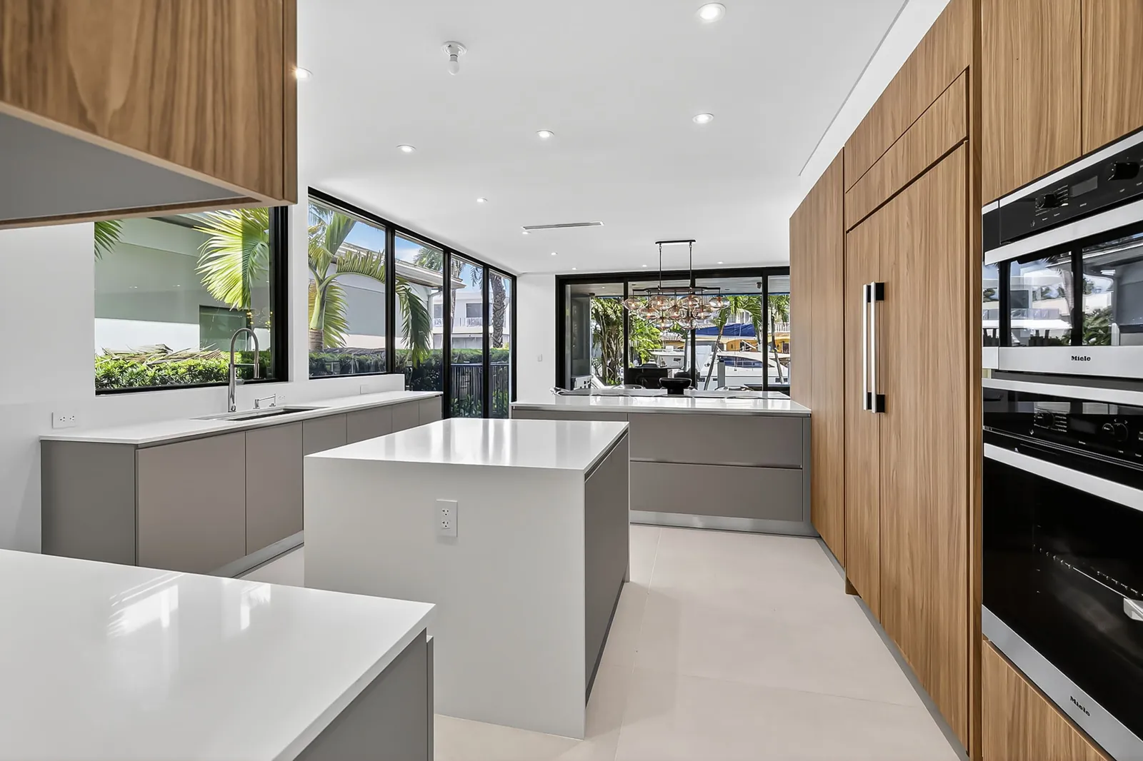 Modern kitchen with walnut cabinetry, white island and a view through to the yard