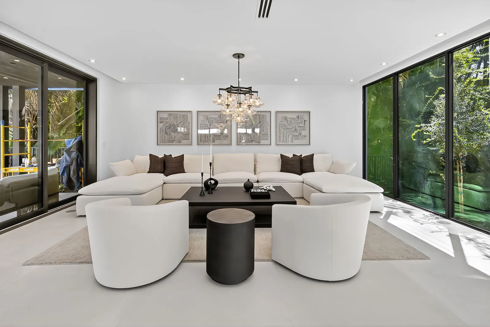 Bright living room with a white sectional, chandelier and sliding glass walls to the garden