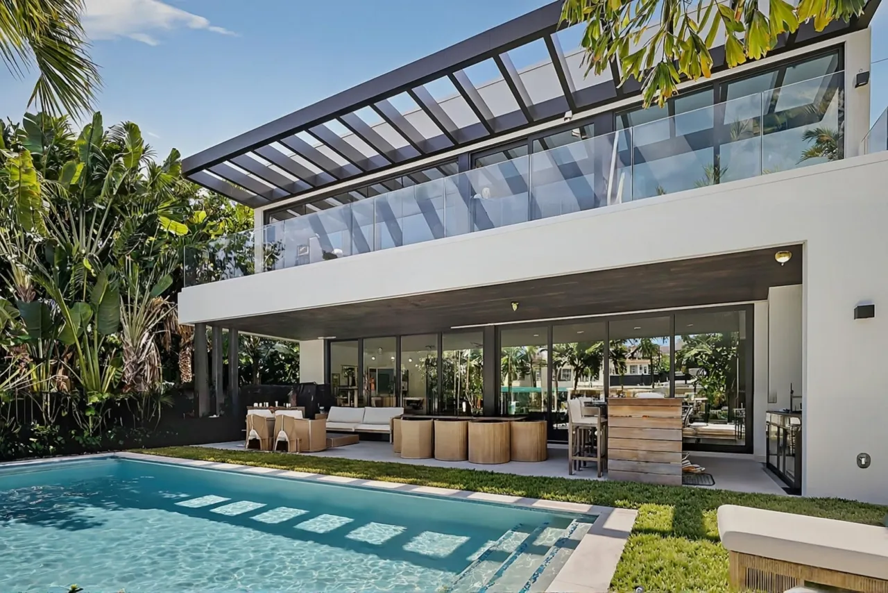 Modern canal-front home with a lap pool, covered terrace and glass walls opening to the garden
