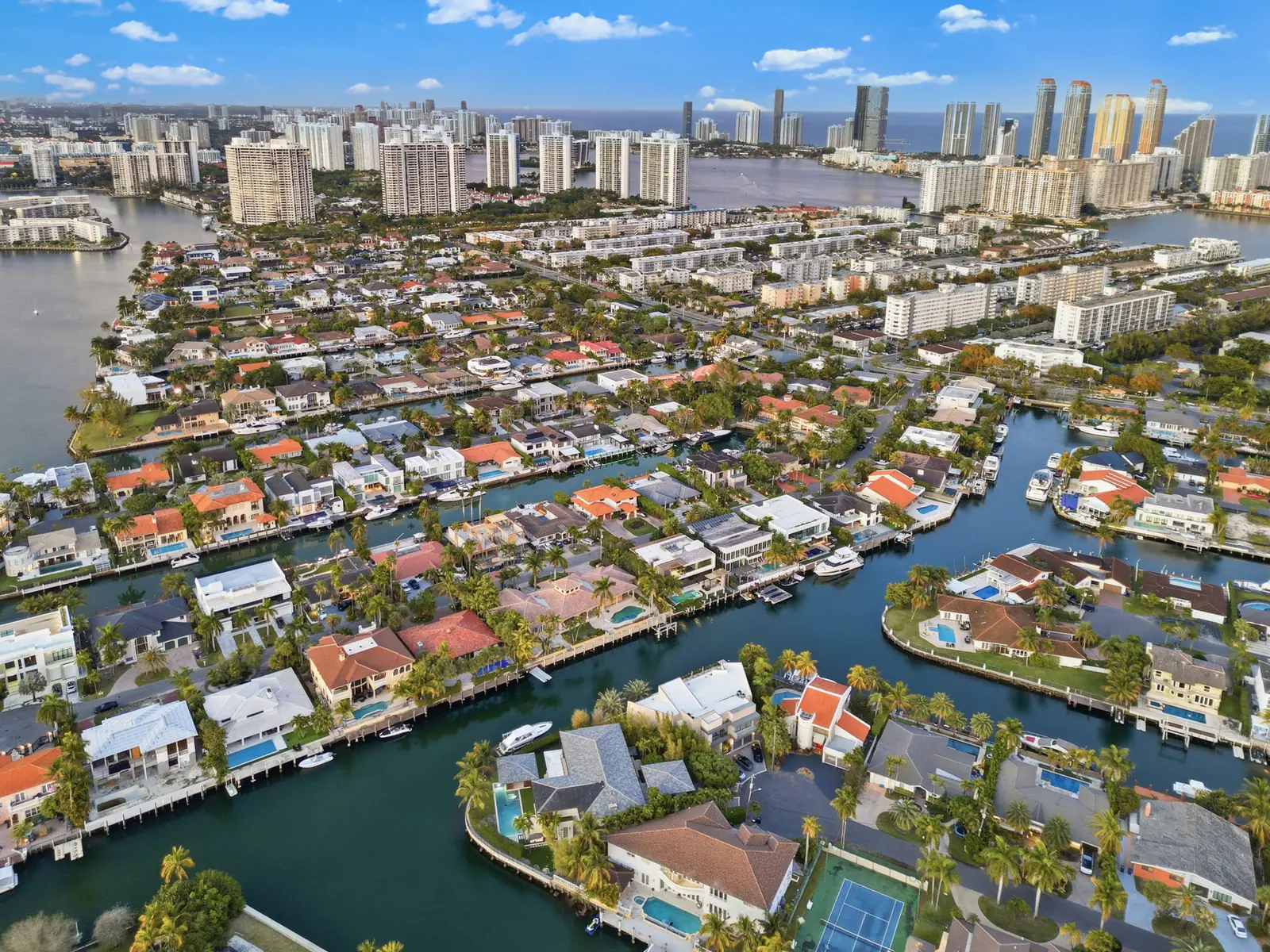 Drone aerial of waterfront canal homes in North Miami Beach with the Sunny Isles skyline